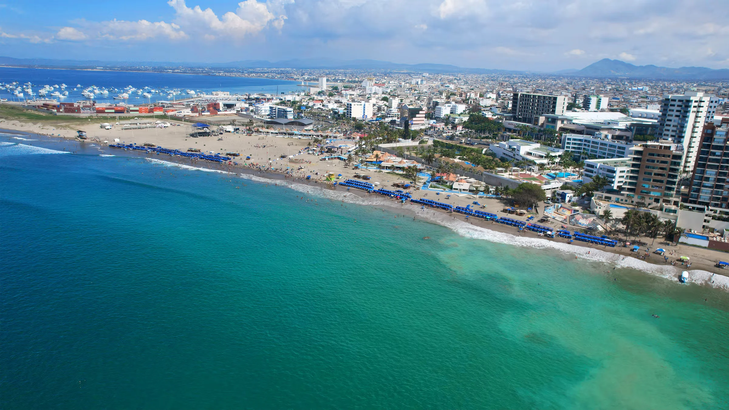 Playa El Murciélago con malecón al fondo y mar abierto.